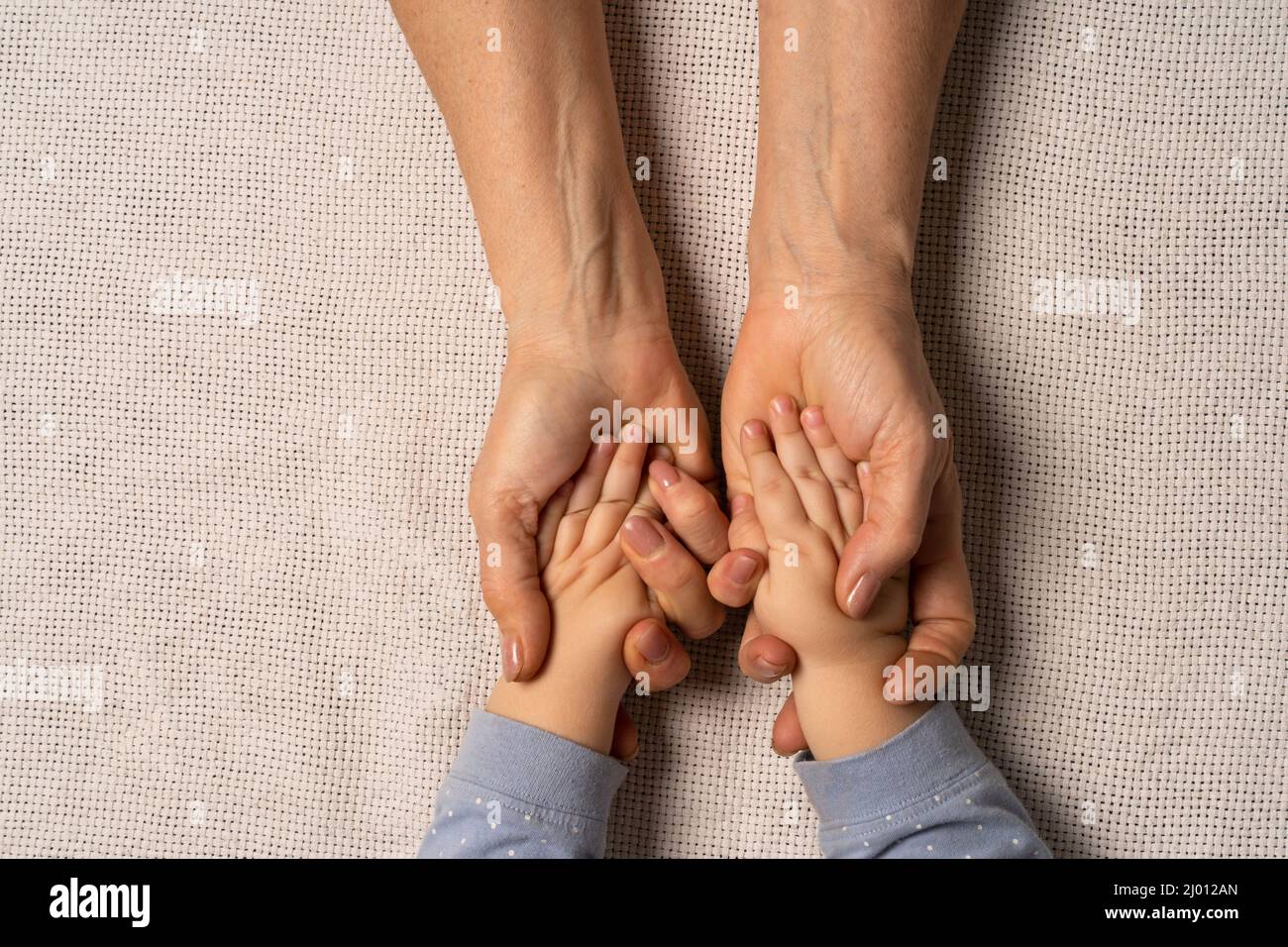 Grandma's hands are holding baby's hands. Concept taking care of the baby , soft skin, great-grandmother and great-grandson. Stock Photo