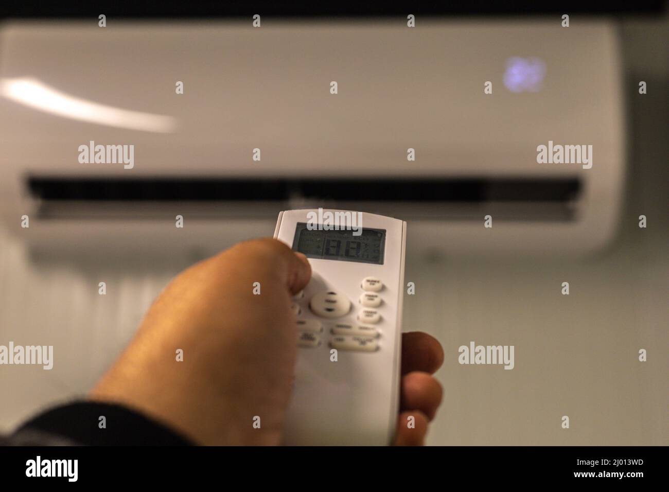 hand with the air conditioner control to set the desired temperature