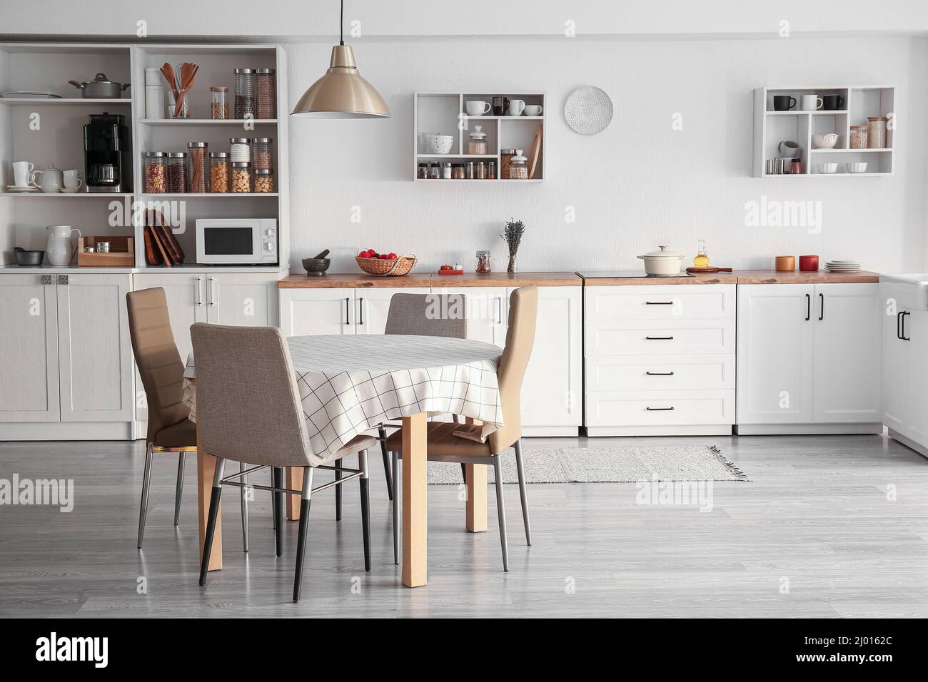 Interior of light modern kitchen with white counters, dining table and ...