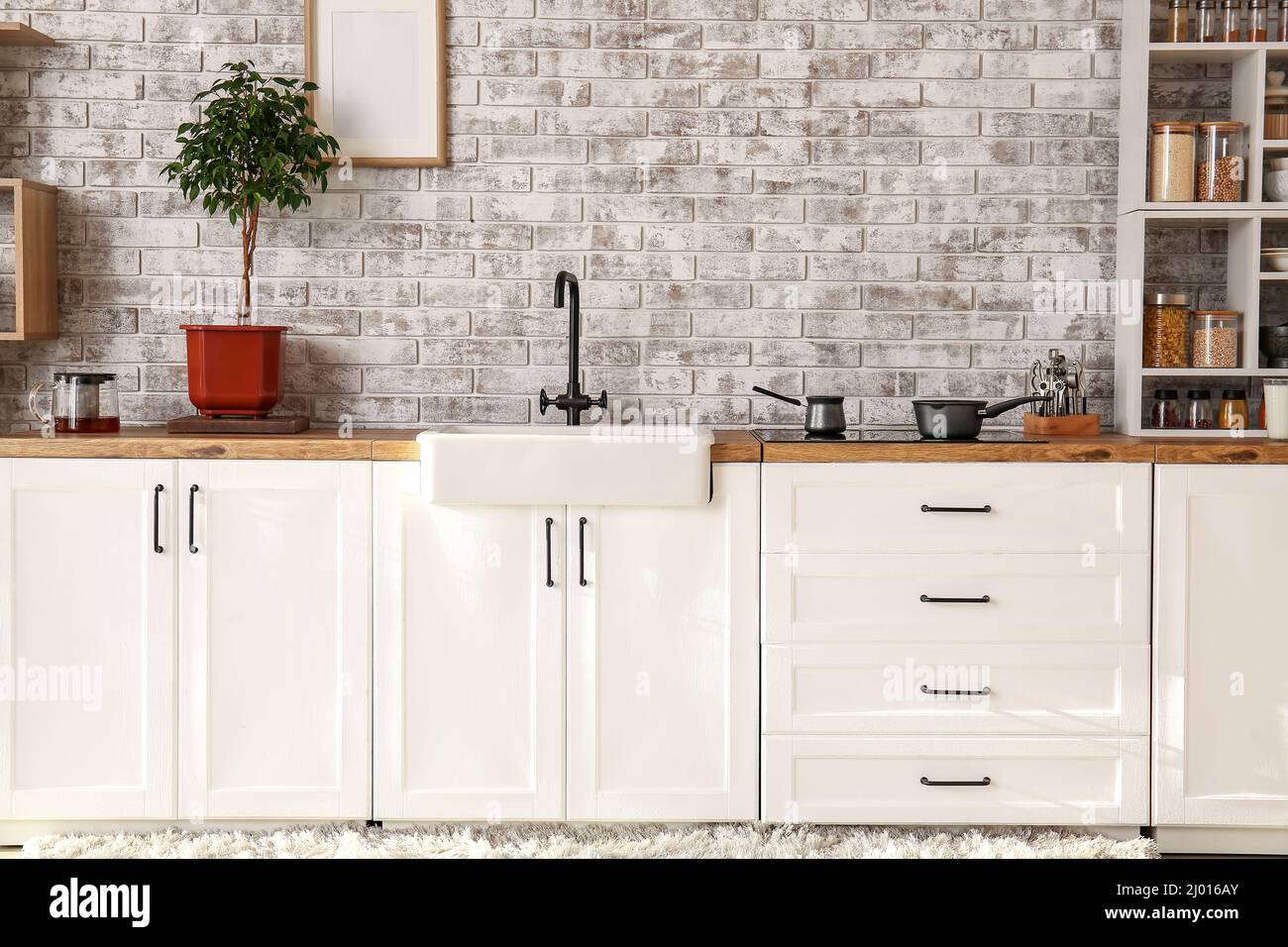 Interior of modern kitchen with white counters and brick wall Stock ...