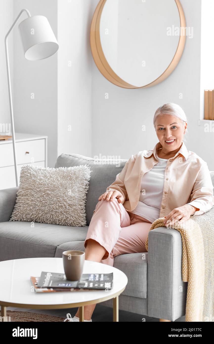 Mature woman sitting on soft sofa at home Stock Photo - Alamy