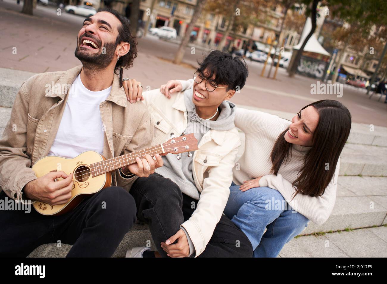 Happy people singing outdoors sitting in street. Group of friends