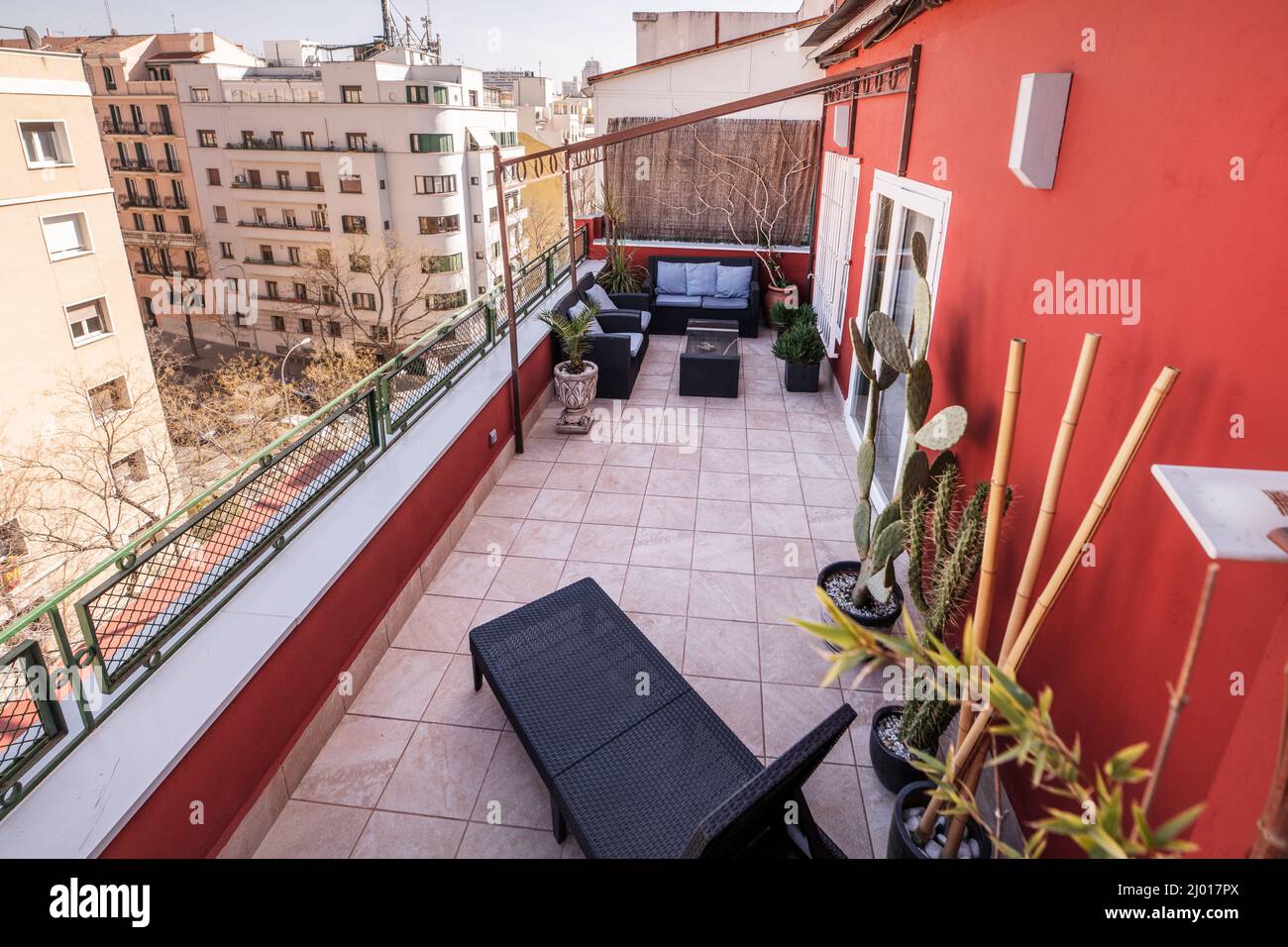 Views of a terrace with rattan furniture, plants and red painted walls Stock Photo