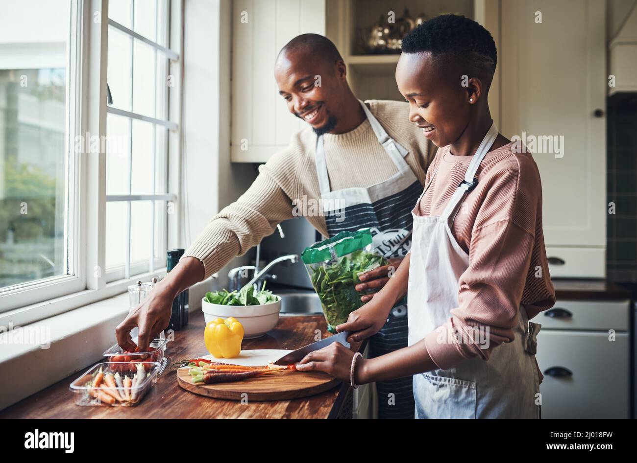 Preparing dinner together. Cropped shot of an affectionate young couple preparing dinner in their kitchen. Stock Photo