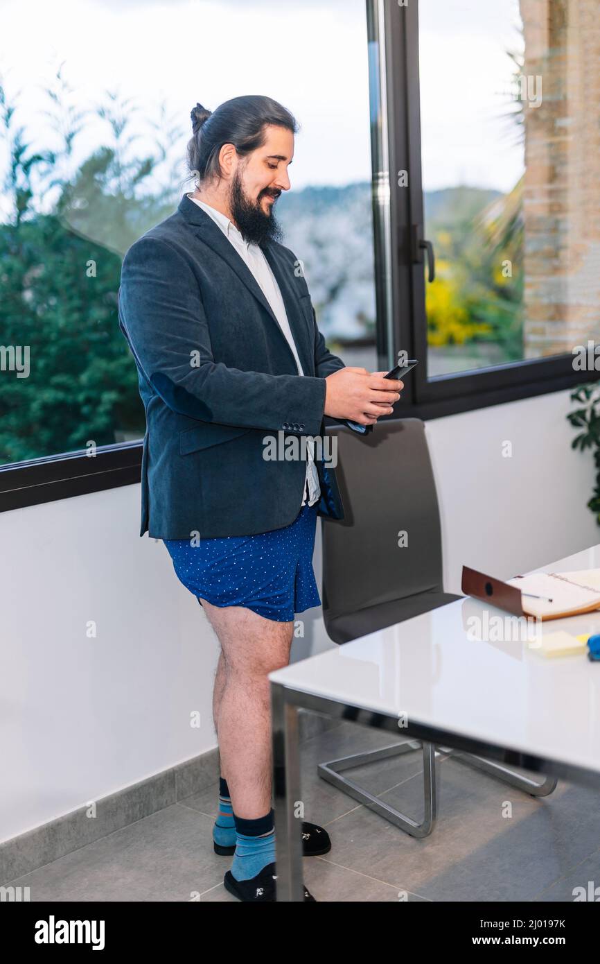 young businessman looking at mobile phone standing without trousers Stock Photo