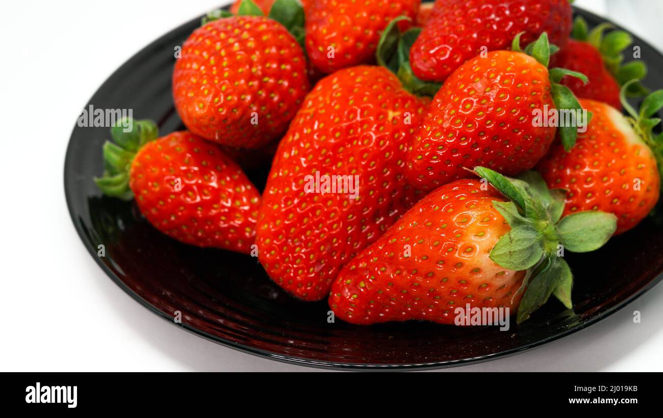 Strawberries on black plate isolated on white background Stock Photo ...