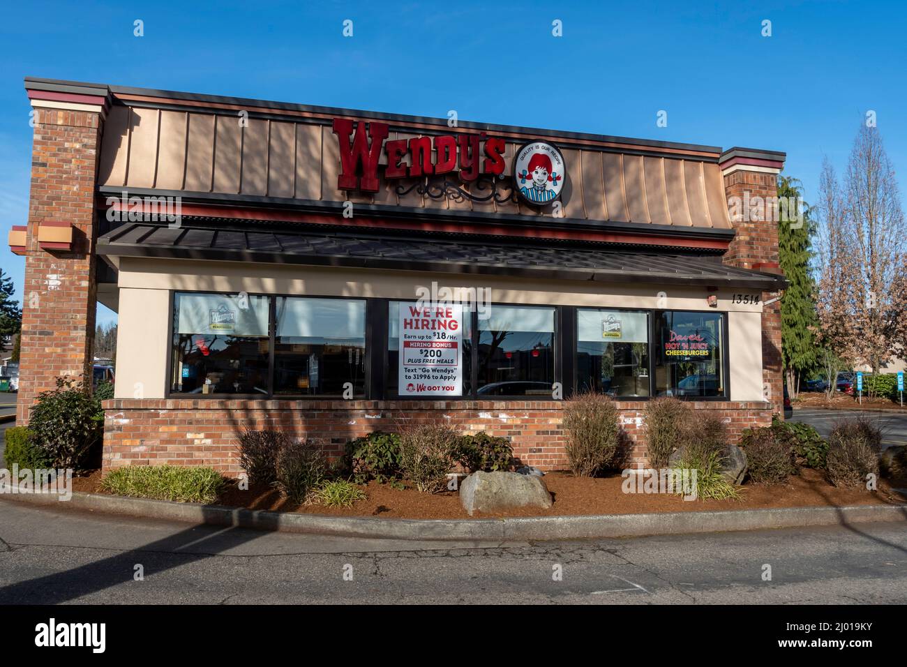 Woodinville, WA USA - circa February 2022: Selective focus on a Now Hiring sign inside a Wendy's Fast Food Restaurant window on a bright, sunny day. Stock Photo