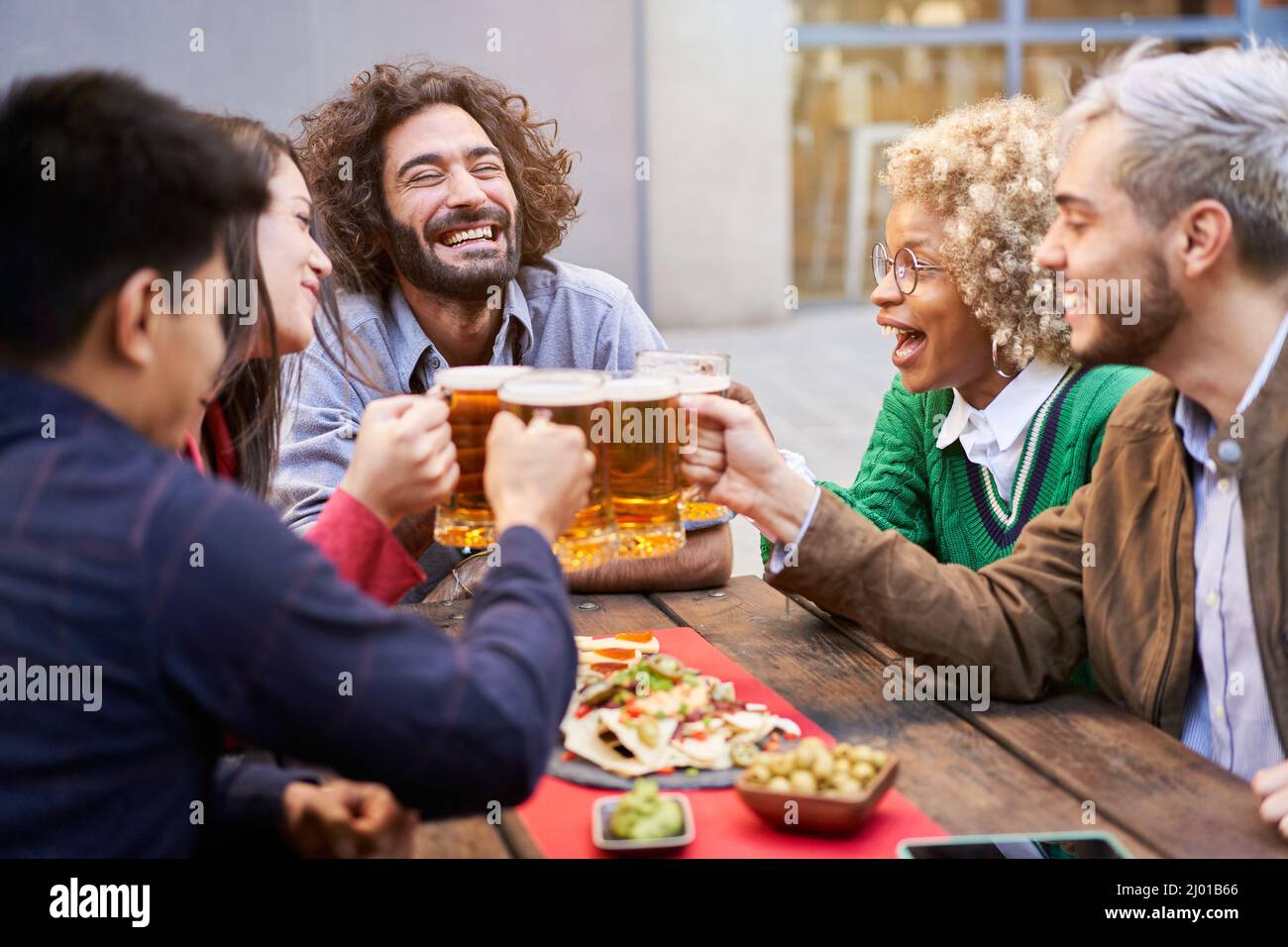 Happy cheerful people toasting beers. Smiling friends holidays. Stock Photo