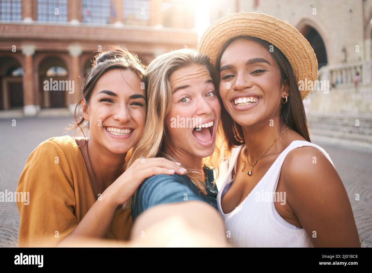 Three funny beautiful girls friends in summer clothes taking a selfie outdoors at the touristic urban center city Stock Photo