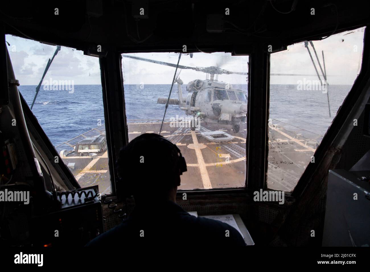PHILIPPINE SEA (March 14, 2022) Lt. j.g. Jian Miclat, from Chula Vista, California, acts as the helicopter control officer and coordinates with the bridge and landing signalman officer for the launch of a MH-60R helicopter assigned to Helicopter Maritime Strike Squadron (HSM) 51 from the deck of the Arleigh Burke-class guided-missile destroyer USS Dewey (DDG 105) while conducting routine operations underway in the U.S. 7th Fleet area of responsibility. Dewey is assigned to Destroyer Squadron (DESRON) 15 and is underway supporting a free and open Indo-Pacific. CTF 71/DESRON 15 is the Navy’s lar Stock Photo