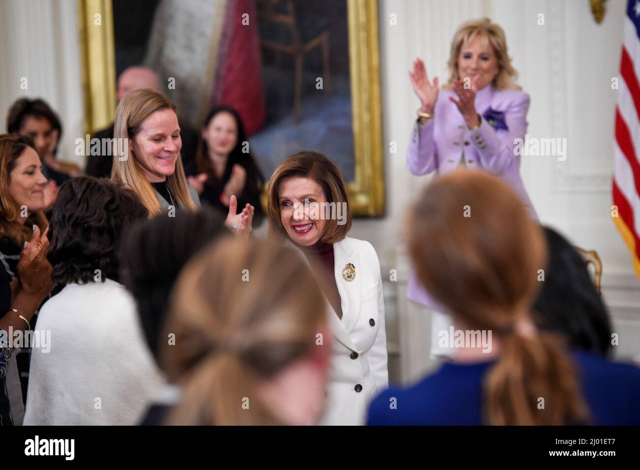 Washington, US. 15th Mar, 2022.Speaker of the United States House of Representatives Nancy Pelosi (Democrat of California), center, is acknowledged by first lady Dr. Jill Biden, right, and White House guests at an event on Equal Pay Day to celebrate Womenâs History Month, in the East Room at the White House in Washington, DC, Tuesday, March 15, 2022. Credit: Rod Lamkey/CNP/dpa/Alamy Live News Stock Photo