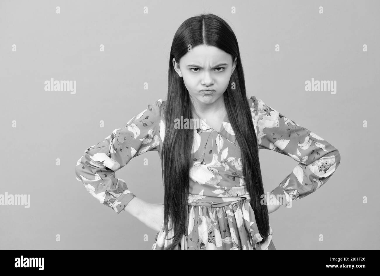 Disobedient spoilt girl child frown keeping arms akimbo blue background, disobedience Stock Photo