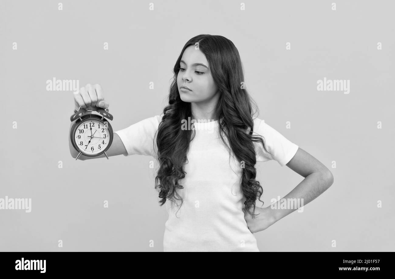 serious kid hold retro alarm clock showing time, punctual Stock Photo