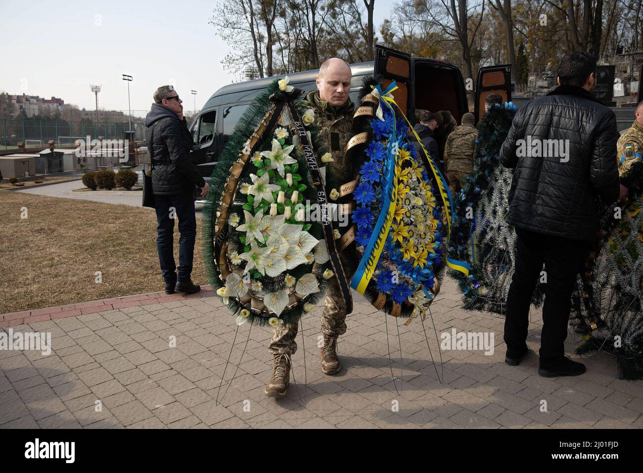 Lviv, Ukraine. 15th Mar, 2022. A Ukrainian solider carries funeral wreath. Three Ukrainian soldiers killed in the March 13th missile attack by Russia at Yavoriv military training ground have been laid to rest. Credit: SOPA Images Limited/Alamy Live News Stock Photo