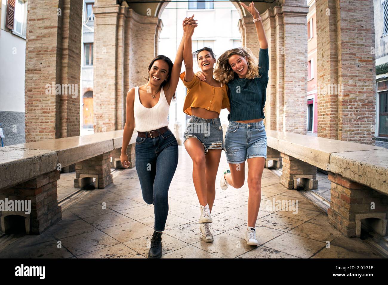 Young happy women happy running to camera laughing excited. Cheerful people making holidays in European city Stock Photo