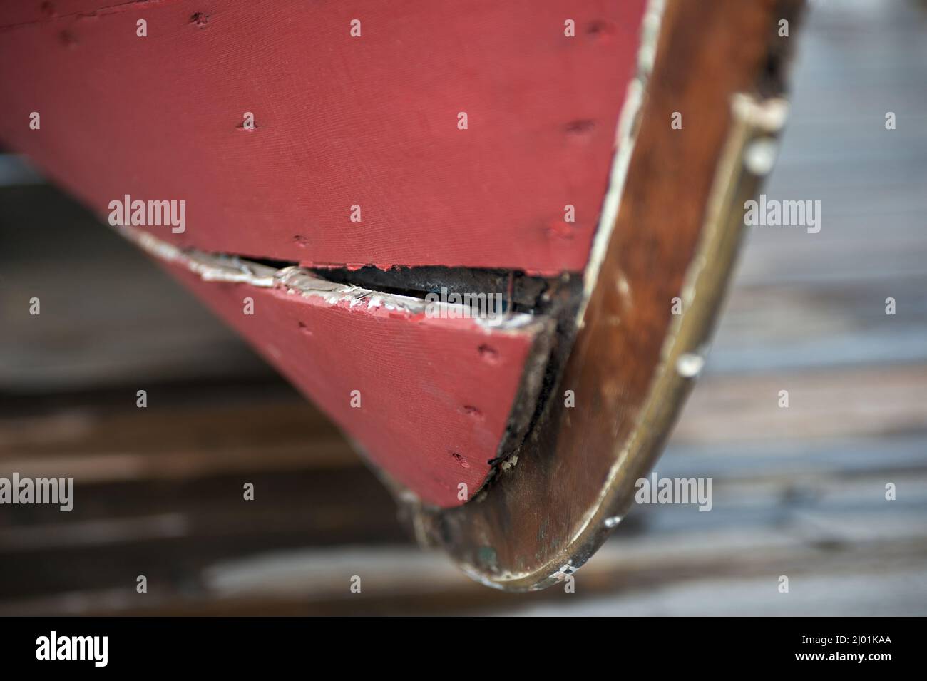 Red boat with its cracked bow in a dry dock. Trouble ahead. Disaster ahead. Warning sign. Problems ahead. Stock Photo