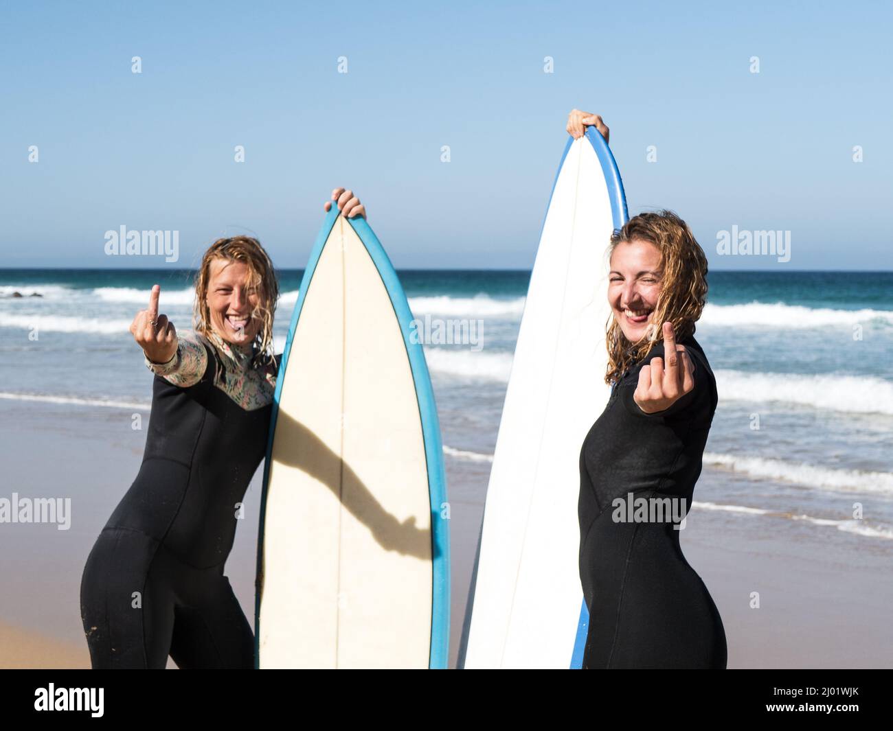 Surfer females on the beach showing middle finger Stock Photo