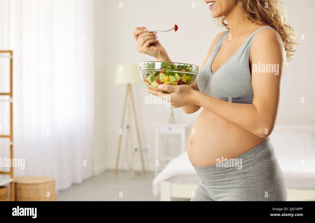 Happy pregnant mother who is expecting baby takes care of her health and eats vegetables Stock Photo