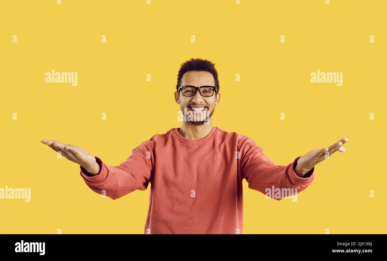 Happy young man in glasses smiling and spreading his arms wide open to hug someone Stock Photo