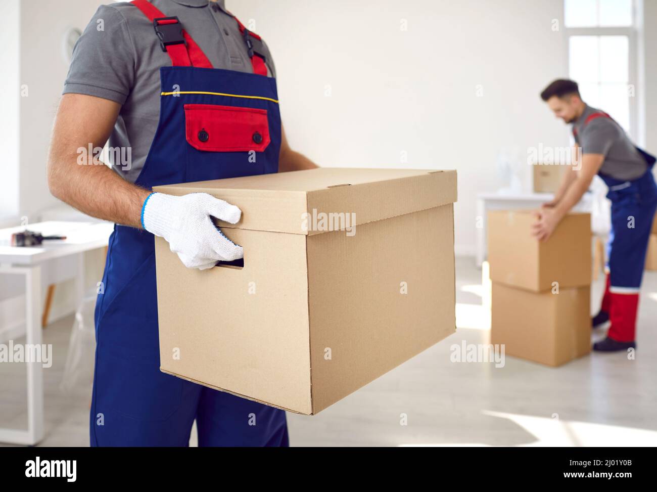 Close up of cardboard box in hands of male employee of moving and delivery company. Stock Photo
