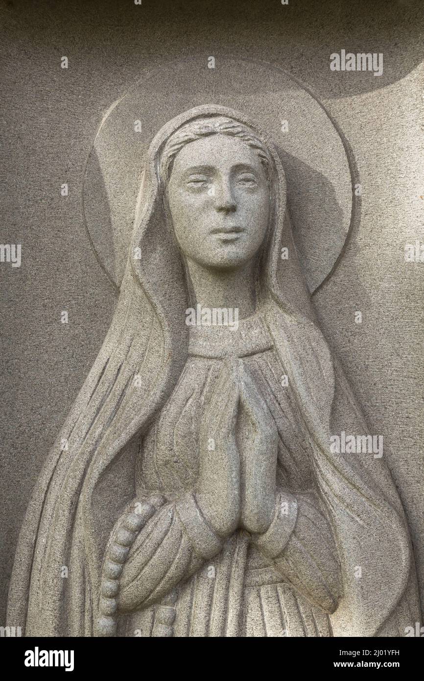 Virgin Mary figurine on granite headstone. Stock Photo