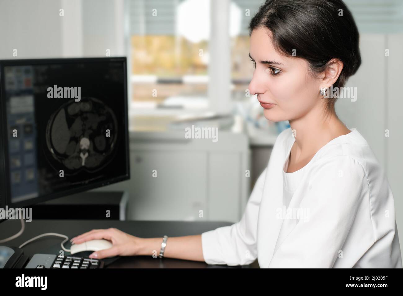 Radiologist woman reading a CT scan. Female doctor running CT scan from control room at hospital Stock Photo
