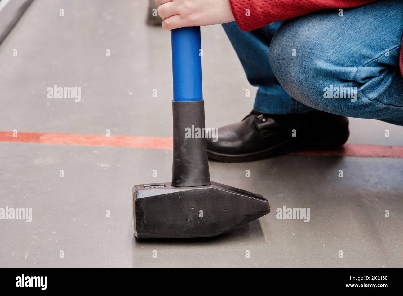 Woman in a building materials store chooses huge, heavy hammer to buy. Close up Stock Photo