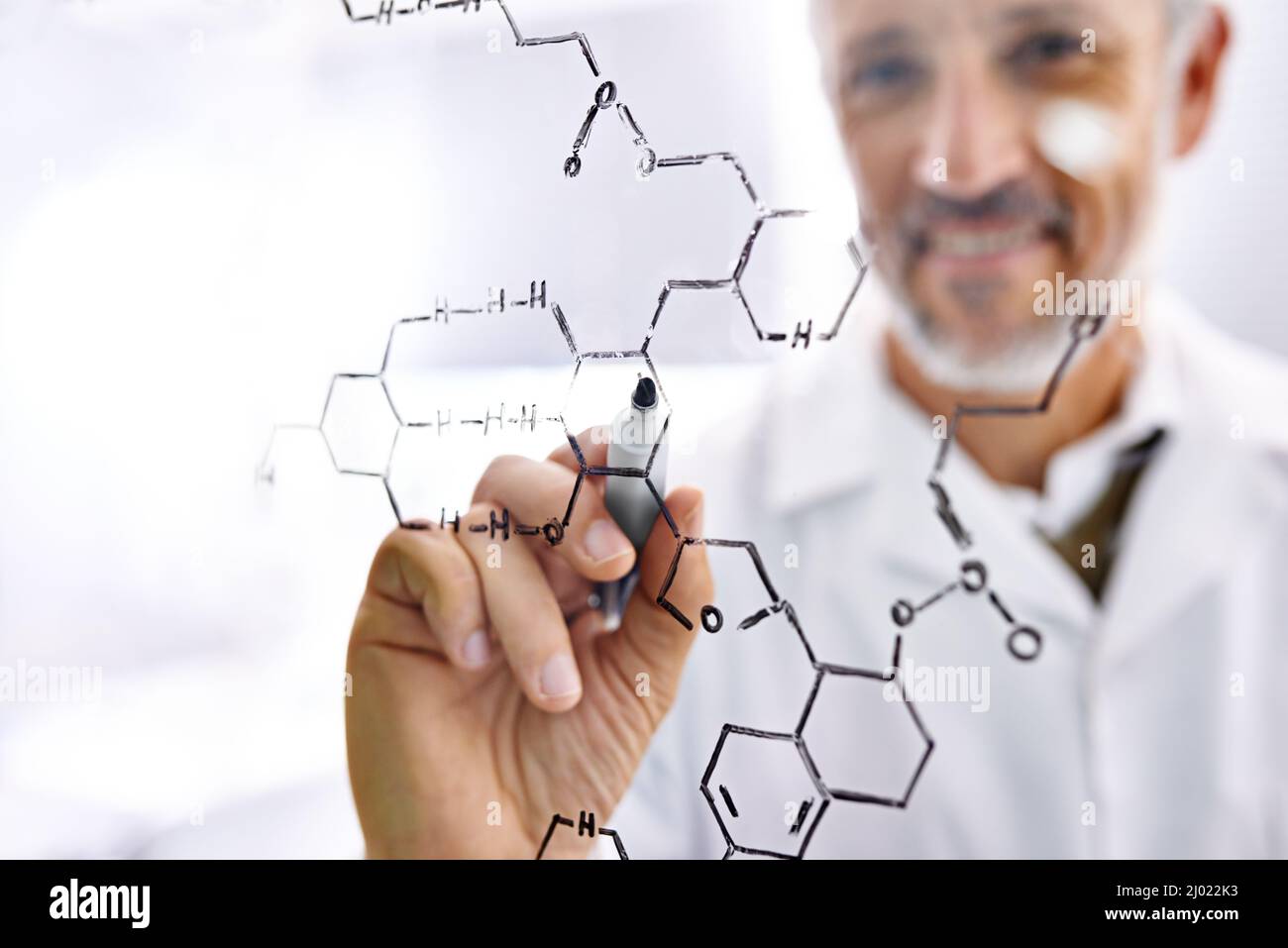 Chemistry makes him happy. Shot of a mature male scientist working with chemistry formulas in his lab. Stock Photo