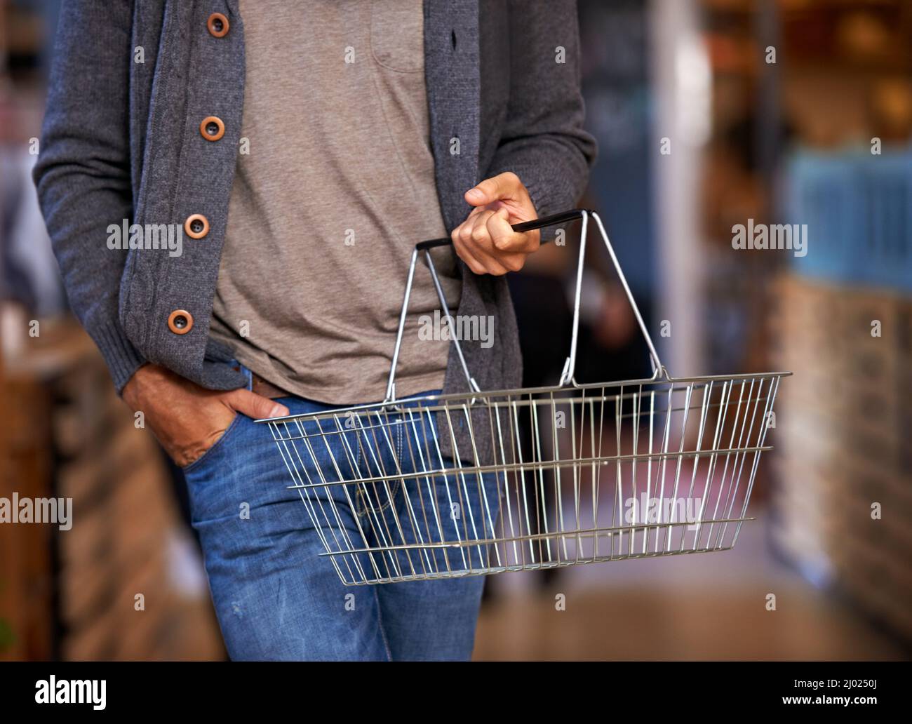 Time for this weeks shopping. Cropped shot of a young man carrying a shopping basket and walking in a grocery store. Stock Photo