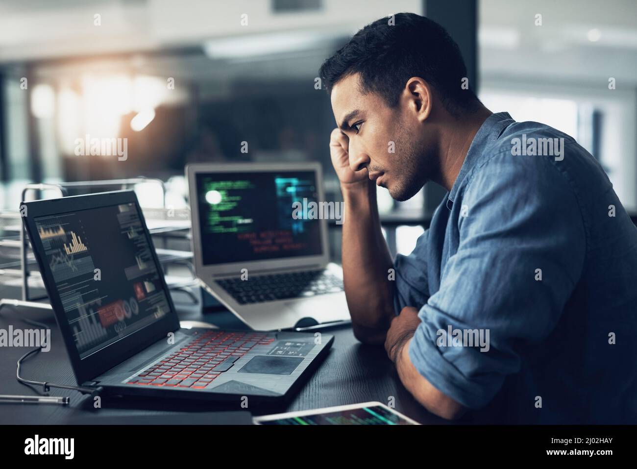Lifes a game with no reset on the end. Shot of a young man suffering from a headache while using a laptop in a modern office. Stock Photo