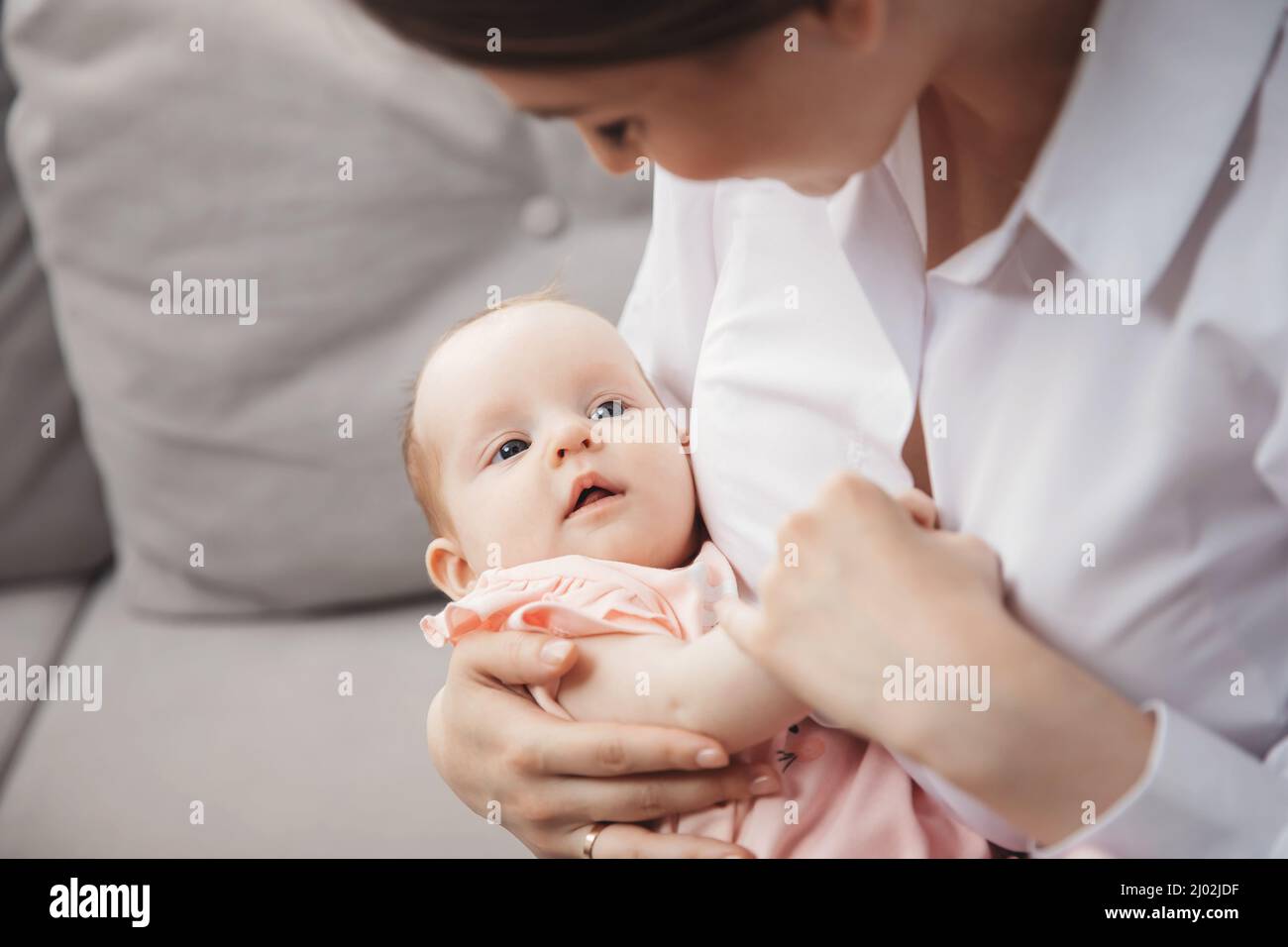 Young mother holds newborn daughter in arms, maternal instinct. Stock Photo
