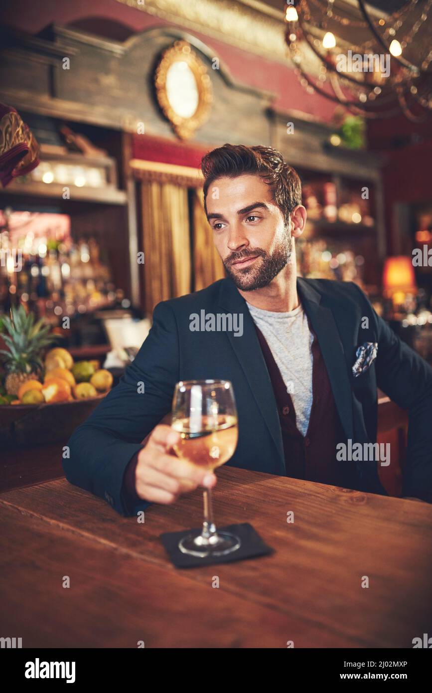 Relaxing with his favourite drink. Cropped shot of a young man sitting in a bar. Stock Photo