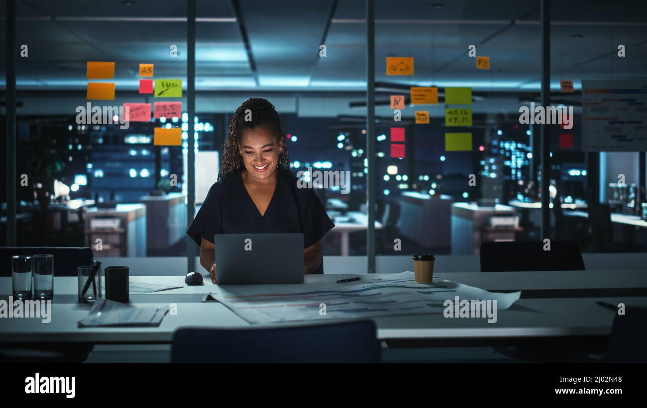 Portrait of African American Businesswoman Working on Laptop Computer in Big City Office Late in the Evening. Female Executive Director Managing Digit Stock Photo