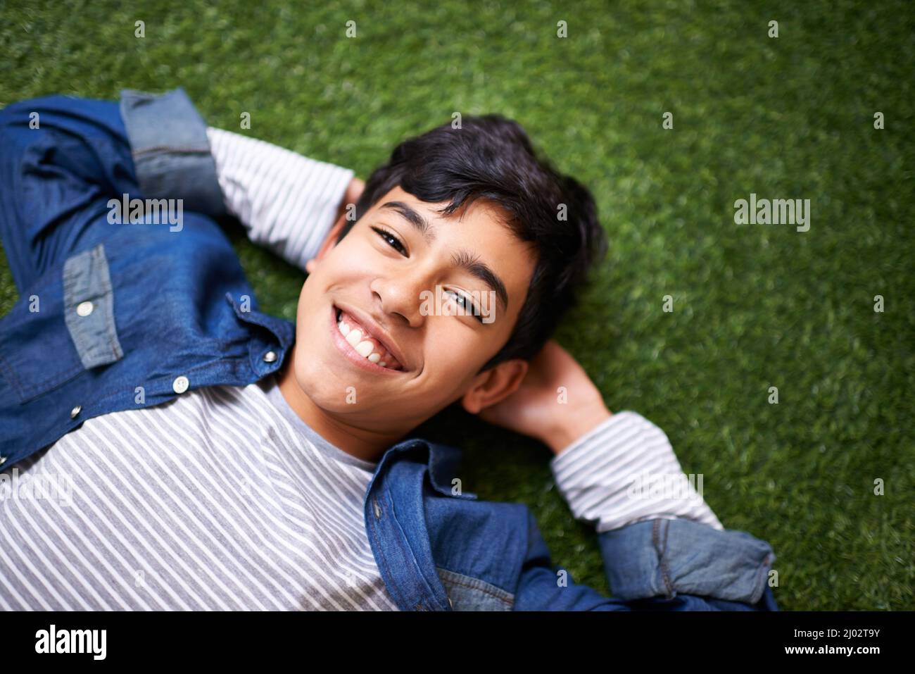 Its awesome being a kid. A young boy relaxing on the lawn. Stock Photo