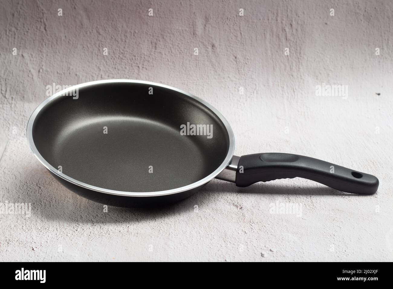 new teflon frying pan on rustic light background Stock Photo