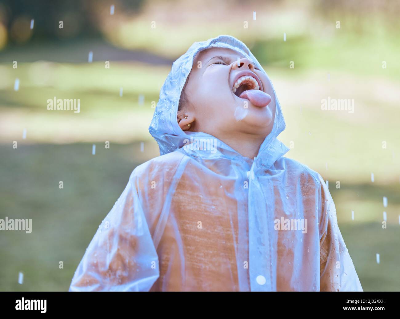 Like water from the heavens. Shot of a little girl sticking her tongue out to catch the rain drops in her mouth. Stock Photo