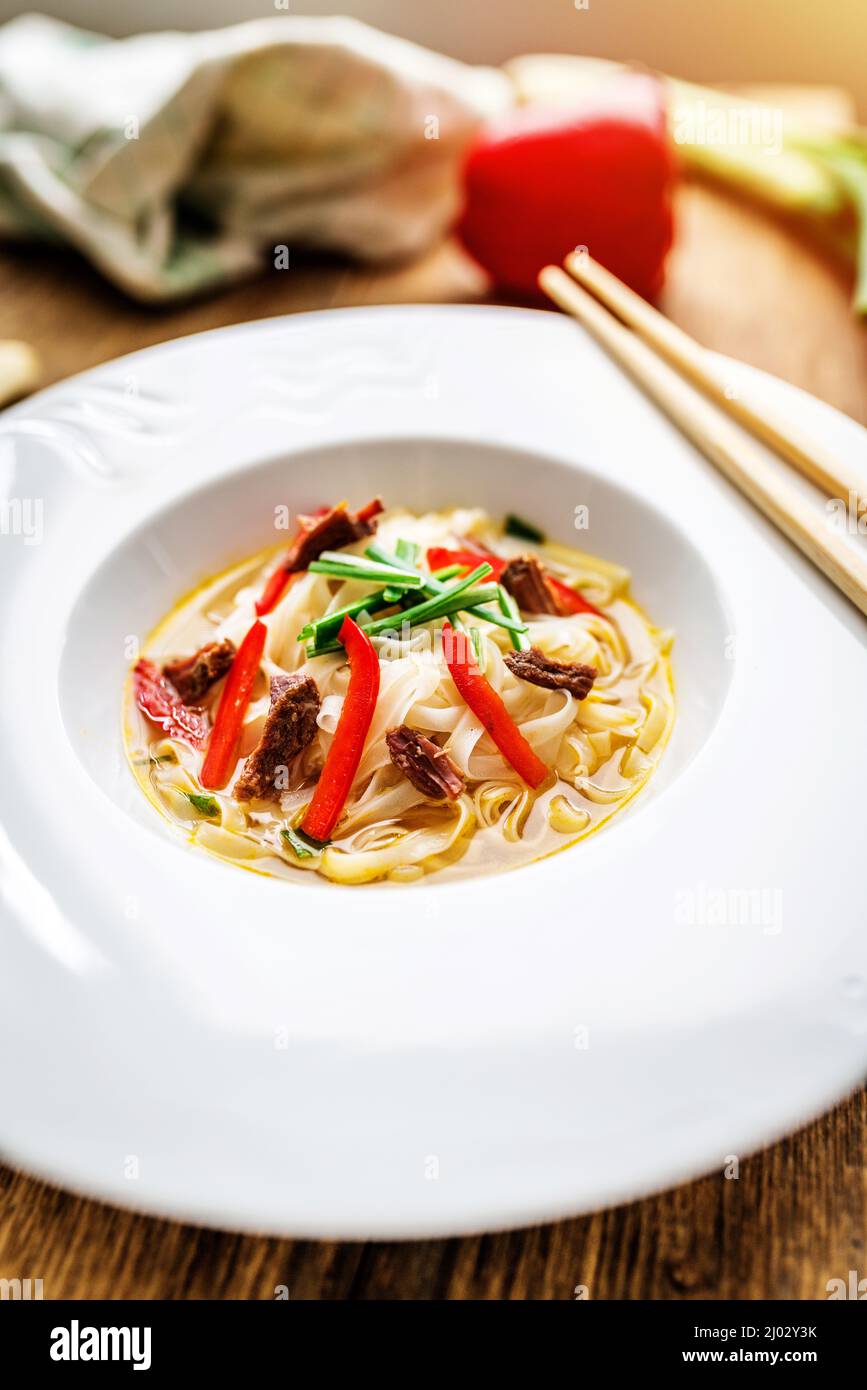 Vietnamese soup pho bo with asian noodles and beef meat on wooden table Stock Photo