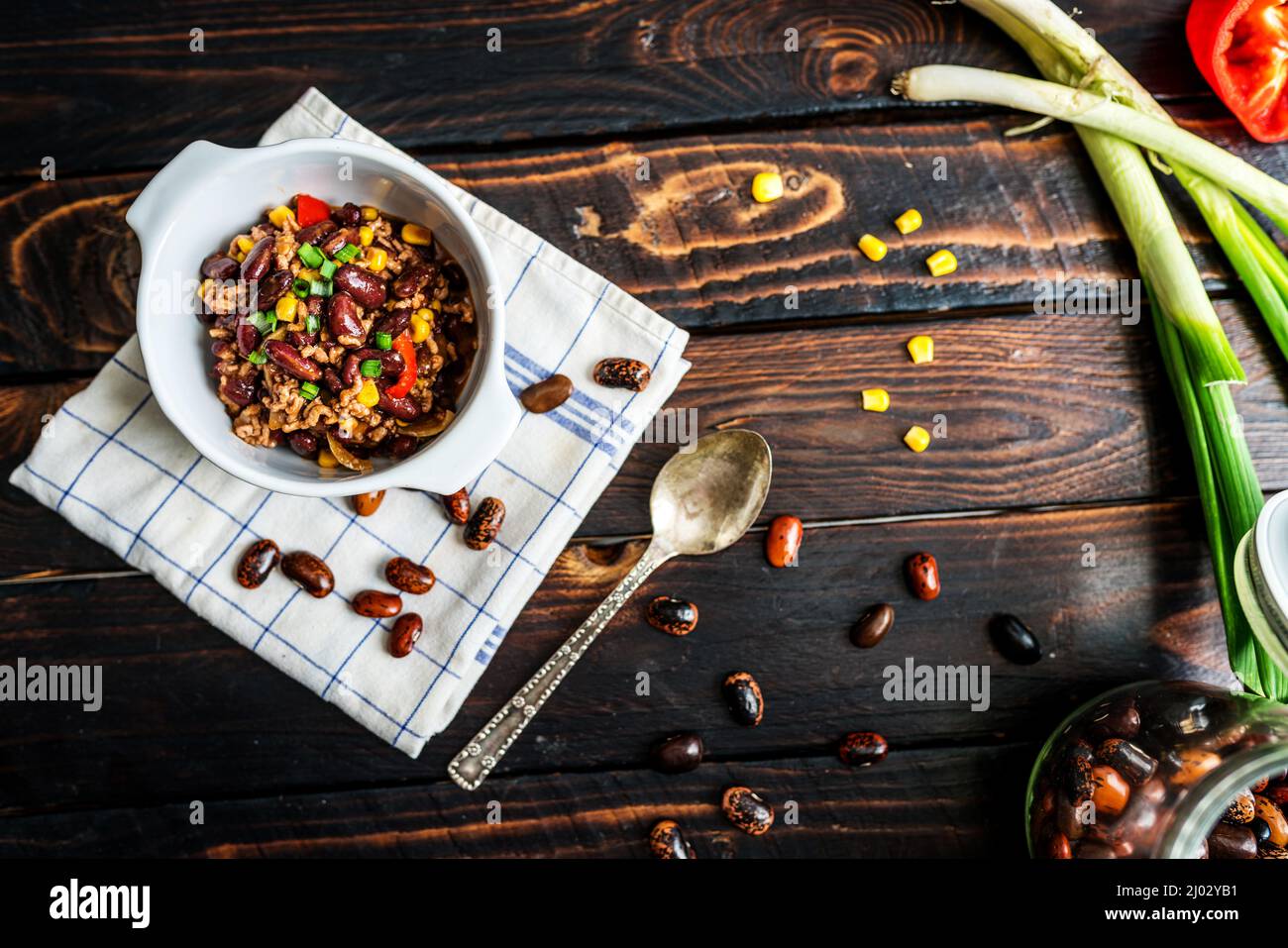 Mexican chili or chilli con carne. Cooked kidney bean, minced meat, chili, corn and pepper in pan  on wood table Stock Photo