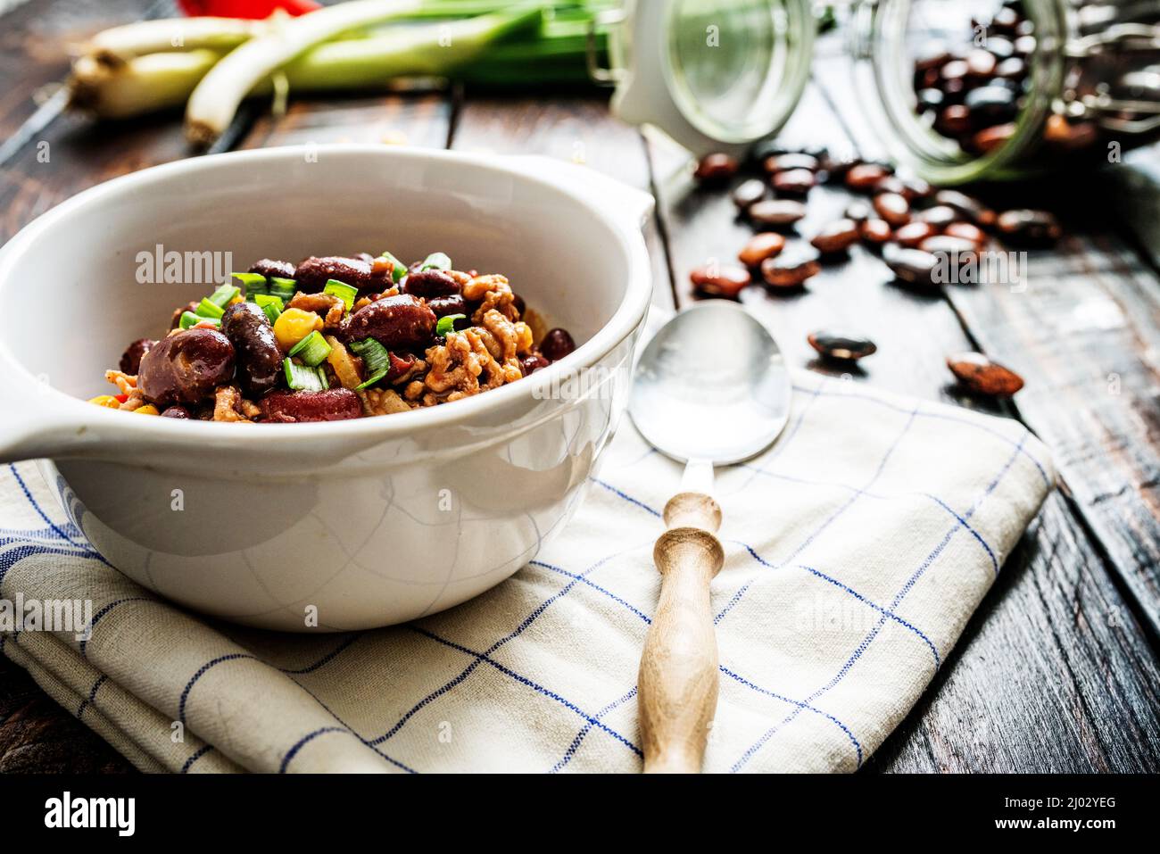 Mexican chili or chilli con carne. Cooked kidney bean, minced meat, chili, corn and pepper in pan  on wood table Stock Photo