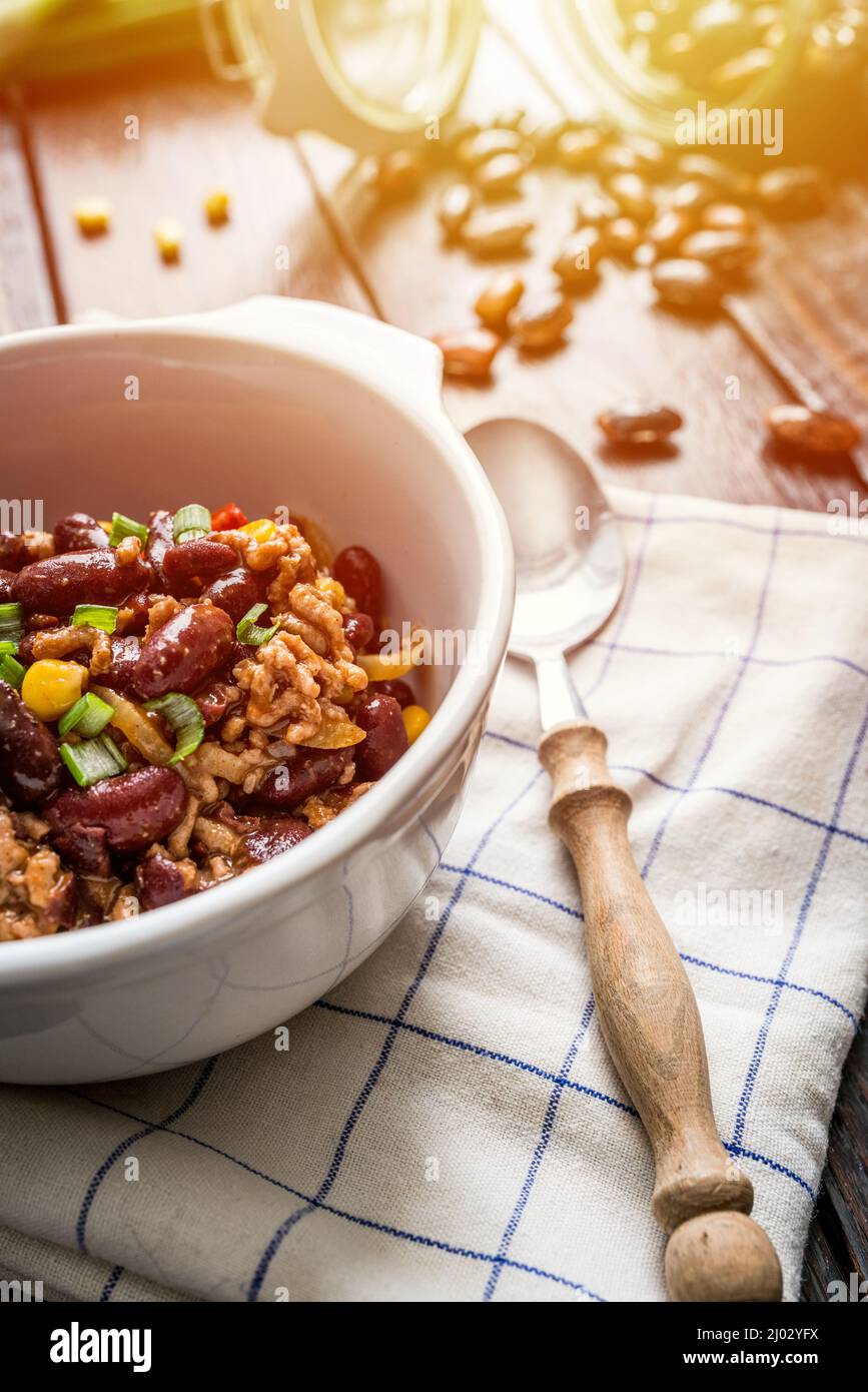 Mexican chili or chilli con carne. Cooked kidney bean, minced meat, chili, corn and pepper in pan  on wood table Stock Photo