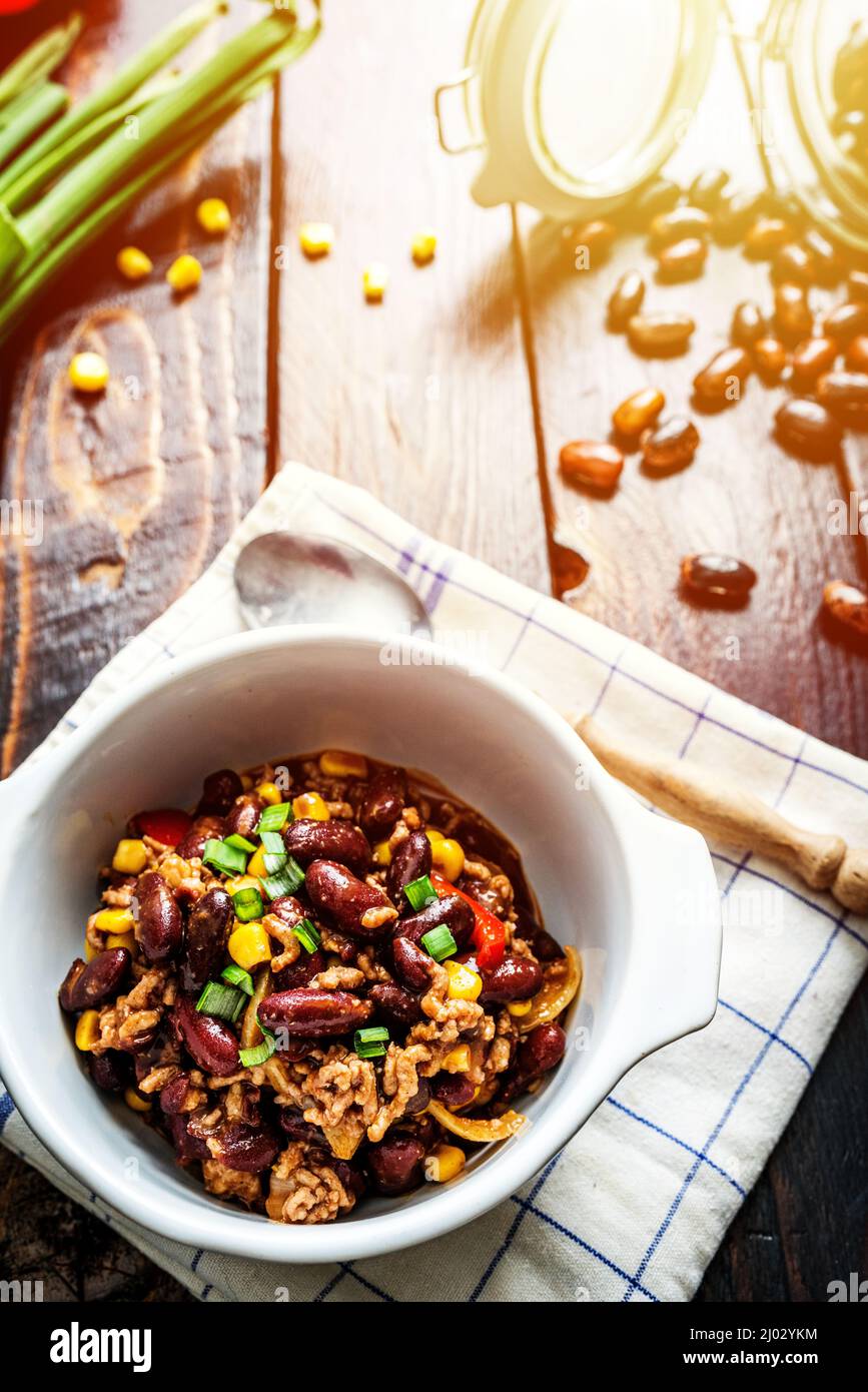 Mexican chili or chilli con carne. Cooked kidney bean, minced meat, chili, corn and pepper in pan  on wood table Stock Photo