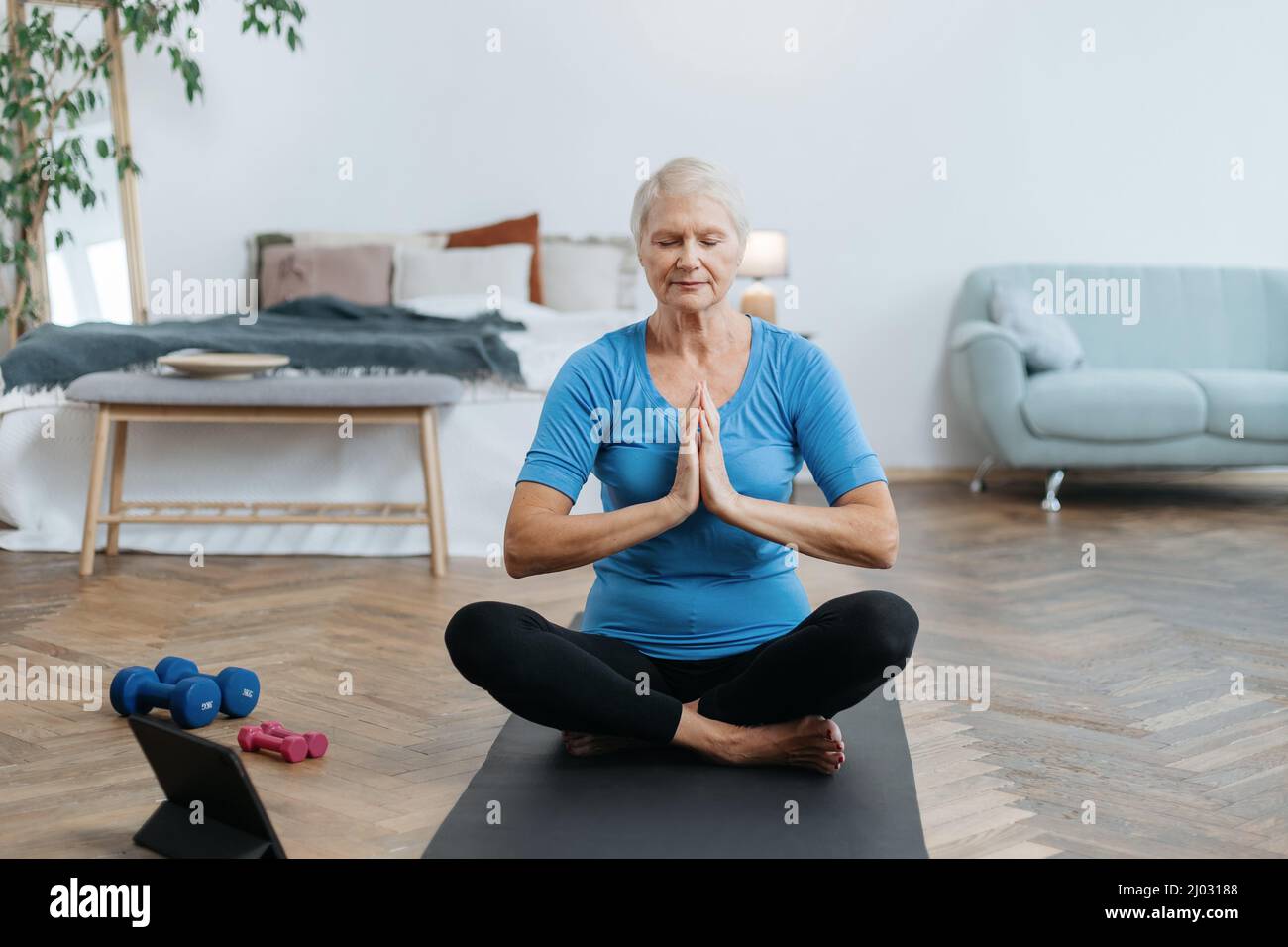 elderly woman sitting in a yoga pose in front of an open laptop Stock ...
