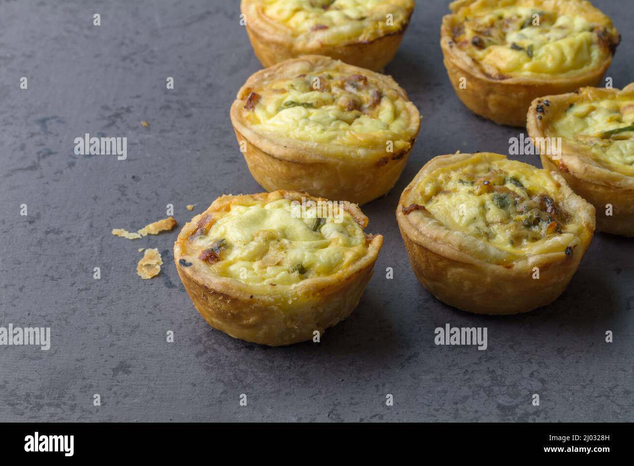 Mini ham, cheese and herb quiches freshly baked on a grey board ready