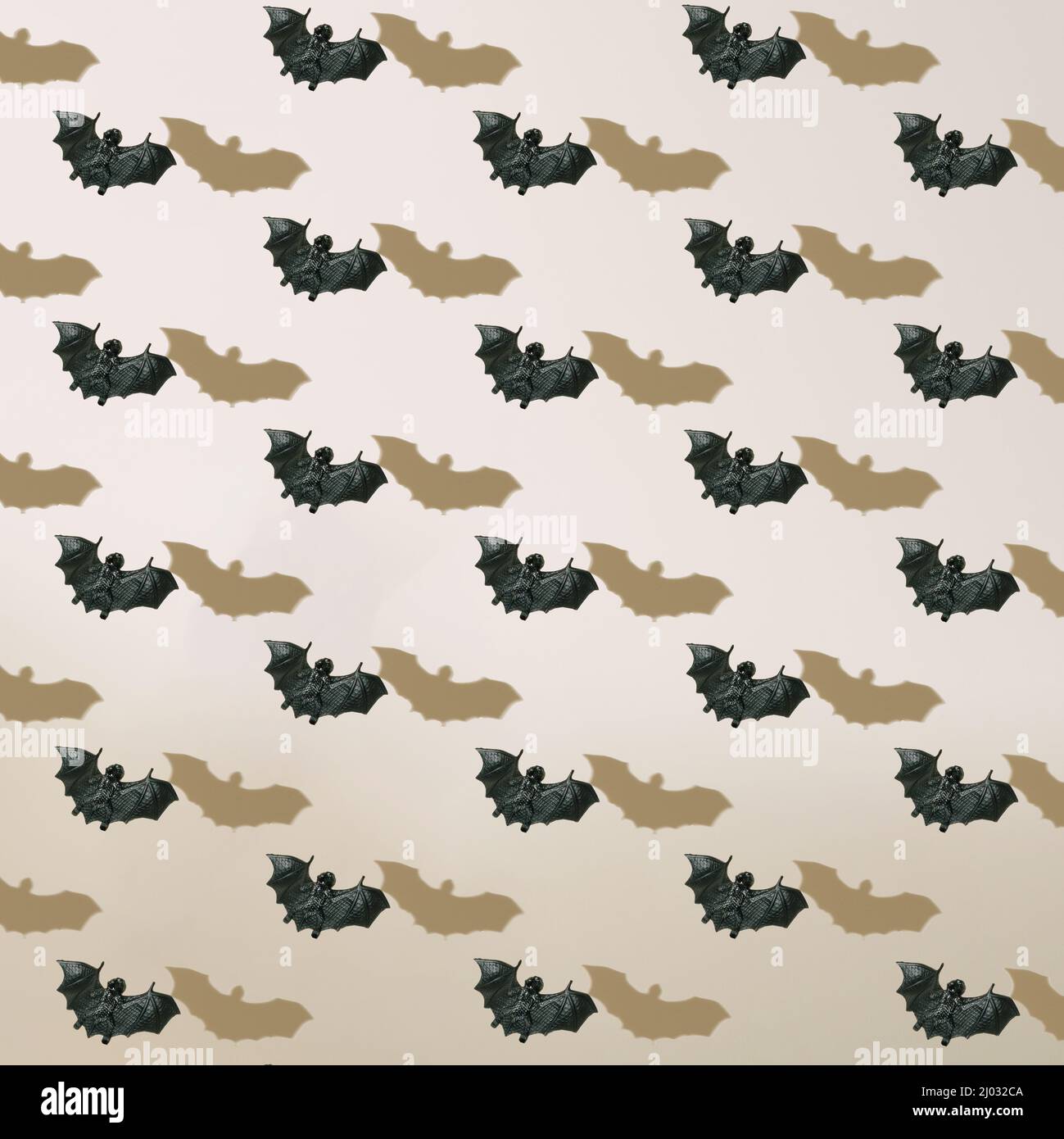 Halloween pattern of black flying bats with shadows on neutral beige background. Stock Photo