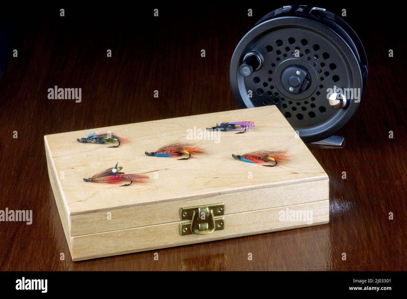 Wooden fishing fly box and flies with fly reel on a polished