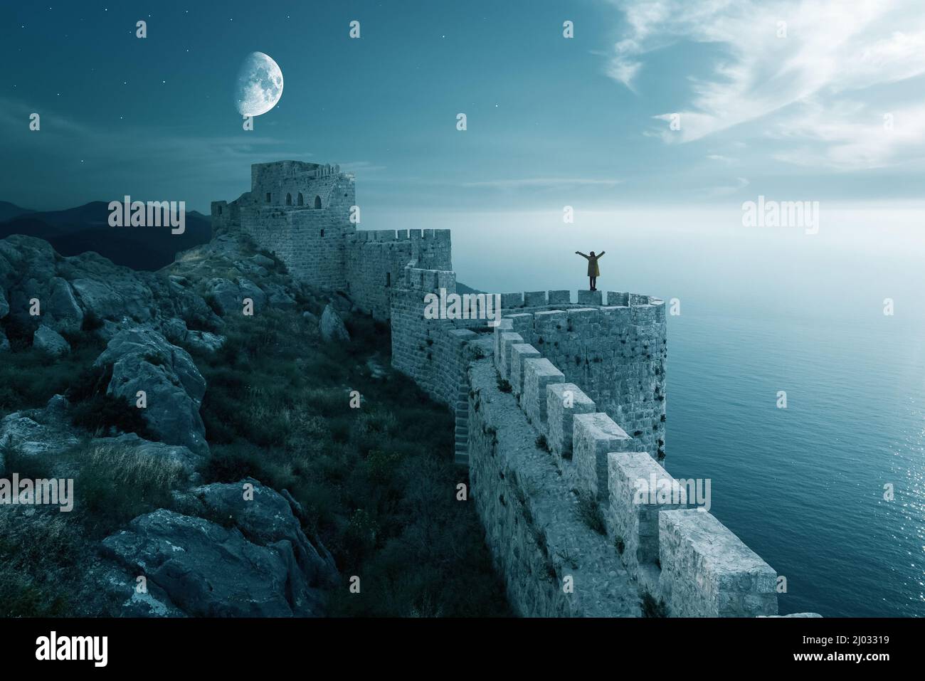 A woman stand ond the walls of a medieval fortress. Wall and tower of a Fotification landscape with moon on sky. High quality photo Stock Photo