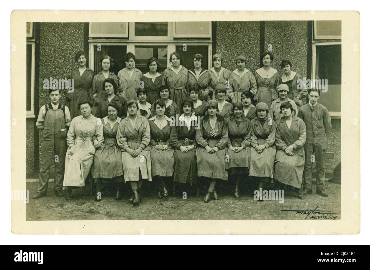 Original late WW1 era postcard of large group of factory workers, possibly munitions workers as the  woman 2nd on left, back row is wearing 'on war service' munitions badge. Photograph by F. Taylor, Wembley, London, U.K. circa 1918. Stock Photo