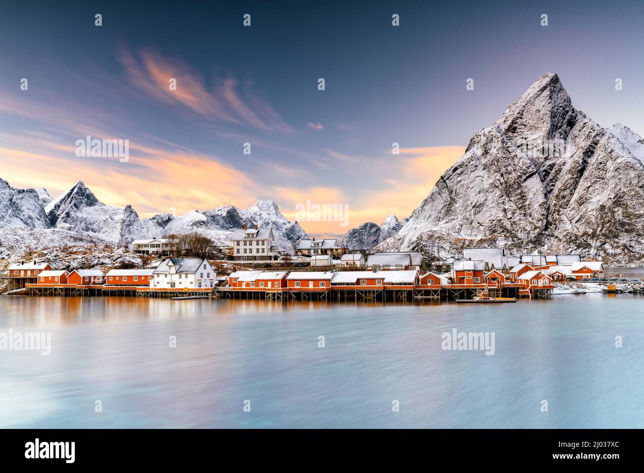 Winter sunset over snowcapped mountains and Sakrisoy village by the frozen sea, Reine, Nordland, Lofoten Islands, Norway, Scandinavia, Europe Stock Photo