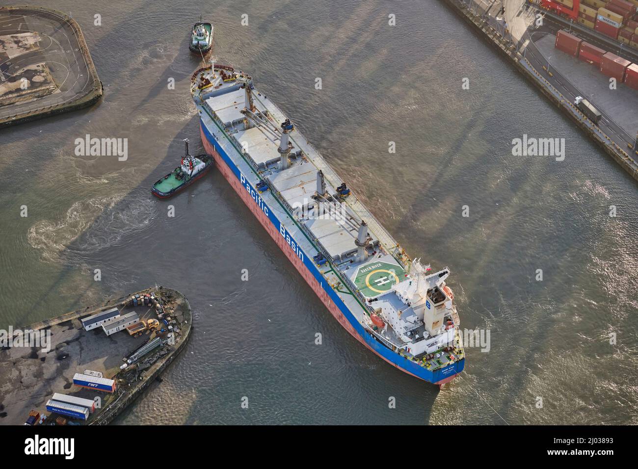 Ship docking at Seaforth Docks, Liverpool, being manoeuvered by two tug boats, Merseyside, North