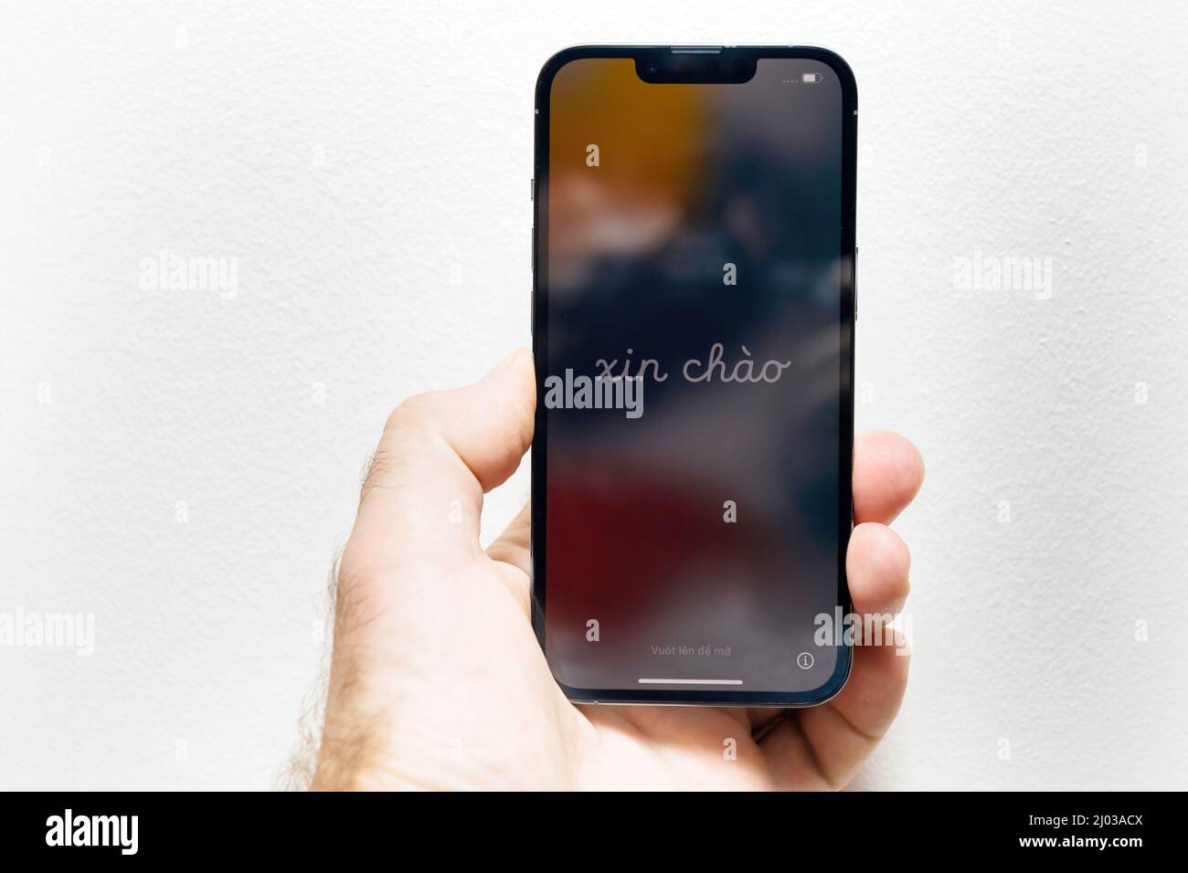Paris, France - Sep 25, 2021: POV male hand after unboxing of new triple camera iPhone 13 Pro Max with Xin Chao text translated from Vietnamese as hello Stock Photo